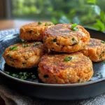 Golden-brown salmon patties frying in a pan with a crispy, well-formed texture.