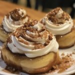 Cinnamon rolls drizzled with maple syrup, topped with cream cheese frosting, served fresh in a baking dish.