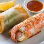 A fresh shrimp roll and a crispy egg roll placed on a plate for comparison.