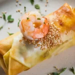 A plate with crispy shrimp egg rolls served with a dipping sauce.