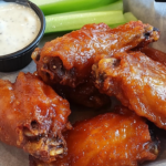 Golden-brown crispy chicken wings served with dipping sauces.