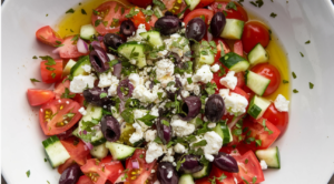 A bowl of Mediterranean salad with fresh vegetables, feta cheese, and olives.