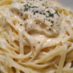 Plate of creamy cream cheese pasta garnished with parmesan and black pepper